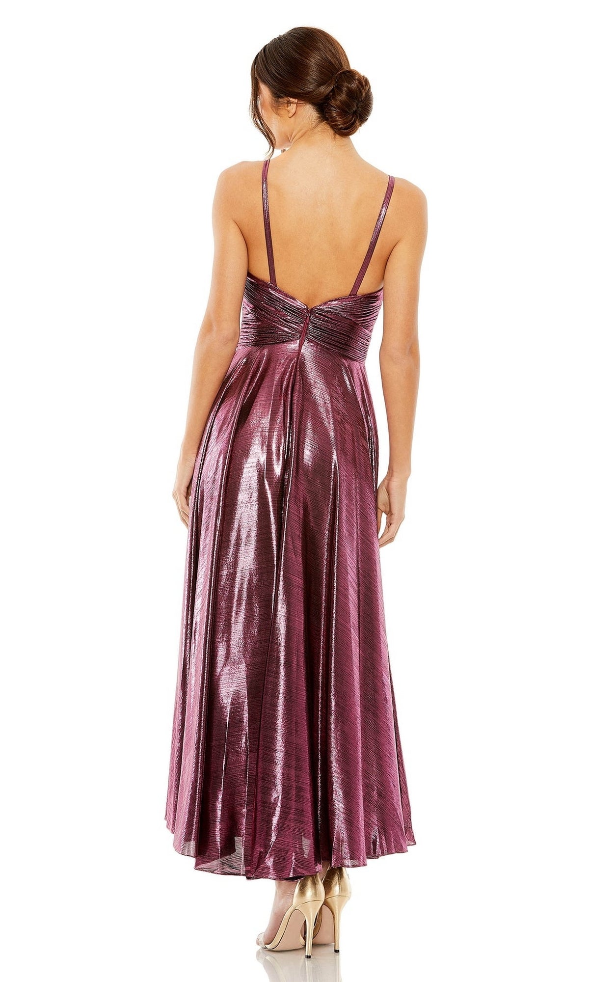 A woman stands with her back to the camera, wearing the sleeveless, backless Mac Duggal 30761 tea-length wedding-guest dress in metallic fabric, paired with nude high heels.